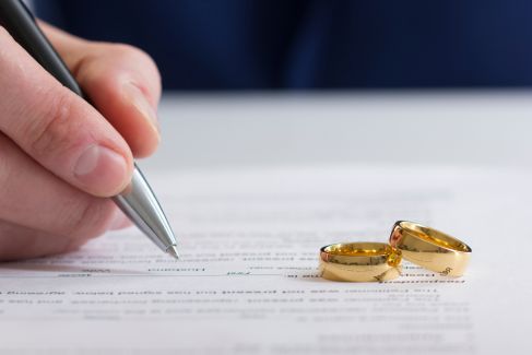 Divorce papers being signed with wedding rings in view